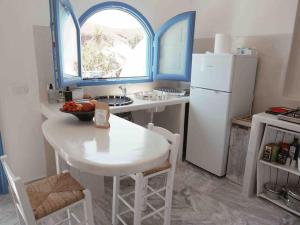 a kitchen with a white table and a white refrigerator at Villa Nidito Santorini in Vlychada Beach
