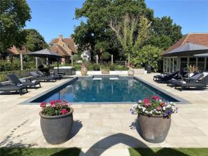a swimming pool with two large pots of flowers next to it at Cloth Hall Barn & Cottages in Smarden