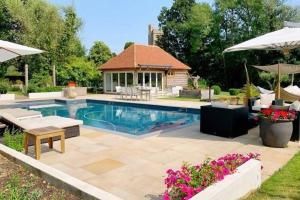 a swimming pool with a patio and a house at Cloth Hall Barn & Cottages in Smarden