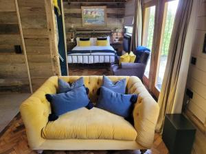 a living room with a yellow couch with blue pillows at Cloth Hall Barn & Cottages in Smarden
