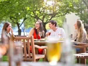 un gruppo di persone seduti a un tavolo con bicchieri da vino di Novotel Queenstown Lakeside a Queenstown