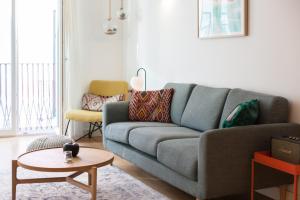 uma sala de estar com um sofá azul e uma mesa em FLH Bairro Alto Balcony with River View em Lisboa