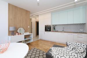 a kitchen with white cabinets and a couch at Słodowiec Residence II in Warsaw