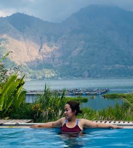 une femme dans une piscine donnant sur un lac dans l'établissement Volcano Living, à Kintamani
