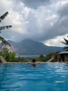 uma pessoa numa piscina com vista para uma montanha em Volcano Living em Kintamani