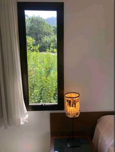 a room with a window and a lamp and a bed at Angra dos Reis - Porto Bali - Apartamento no Complexo Mercur in Angra dos Reis