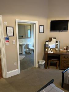 a room with a bathroom with a desk and a television at Admiral MacBride in Plymouth