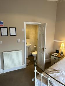 a bedroom with a bed and a bathroom with a toilet at Admiral MacBride in Plymouth