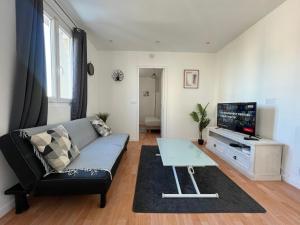 a living room with a couch and a tv at Rue de la paix 3 personnes - 10'min Paris in Les Lilas