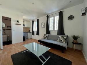 a living room with a couch and a glass table at Rue de la paix 3 personnes - 10'min Paris in Les Lilas