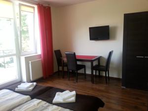 Pokój hotelowy ze stołem, krzesłami i telewizorem w obiekcie Pokoje w Apartamencie Danuta w mieście Gdynia