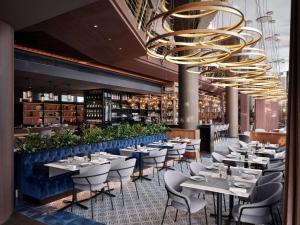 a restaurant with tables and chairs and a chandelier at Sofitel Barcelona Skipper in Barcelona