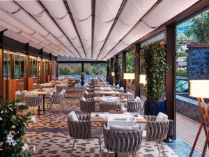 um restaurante com mesas, cadeiras e janelas em Sofitel Barcelona Skipper em Barcelona