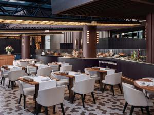 a restaurant with wooden tables and white chairs at Sofitel Barcelona Skipper in Barcelona