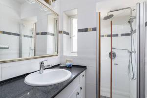 a white bathroom with a sink and a shower at Neta's Central Gem with Bomb Shelter in Tel Aviv in Tel Aviv