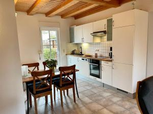 ティンメンドルフにあるFerienhäuser Liethmann Haus 3 W 1の白いキャビネット、テーブルと椅子付きのキッチンが備わります。