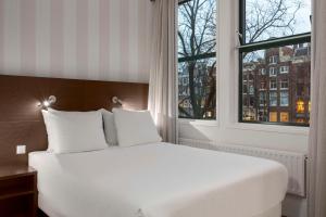 - un lit blanc dans une chambre avec fenêtre dans l'établissement NH City Centre Amsterdam, à Amsterdam