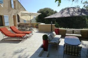 a patio with chairs and tables and an umbrella at Le Grand Saint Paul in Rognes