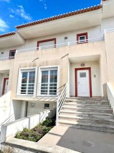 uma casa branca com uma porta vermelha e escadas em Fantastic 3 bedroom Villa - Peniche - Mer&Surf em Atouguia da Baleia
