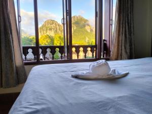 a room with a bed with a window with figurines at Bungalows Le Jardin VANGVIENG in Vang Vieng