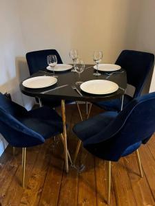 Inviting 3-Bed Apartment in Newcastle upon Tyne في نيوكاسل أبون تاين: طاولة سوداء مع أربعة كراسي وكؤوس للنبيذ