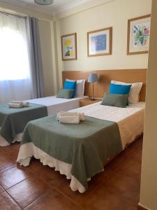 two beds in a hotel room with towels on them at Apartamento Altura T2 in Altura