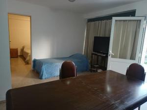 a room with a table and a bed and a television at Departamentos Don Claudio in San Luis