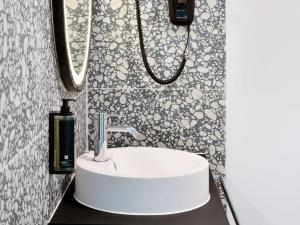 La salle de bains est pourvue d'un lavabo blanc et d'un miroir. dans l'établissement ibis Styles Bredene, à Bredene