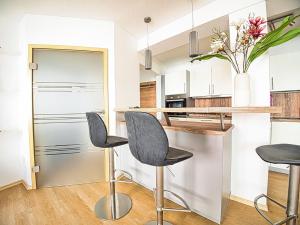 a kitchen with gray stools and a counter with a refrigerator at Ferienwohnung Bergliebe in Berchtesgaden