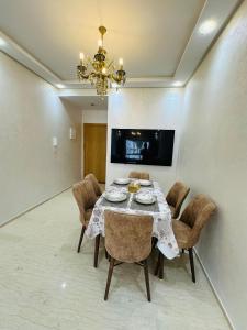 Luxury AÏDA FLAT في طنجة: غرفة طعام مع طاولة مع كراسي وثريا