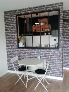 una mesa blanca y dos sillas contra una pared de ladrillo en Studio agréable dans résidence, en Joué-lès-Tours