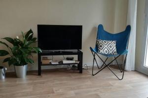 a blue chair in a living room with a television at Studio agréable dans résidence in Joué-lès-Tours
