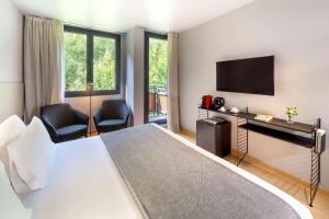 ein Hotelzimmer mit einem Bett und einem Flachbild-TV in der Unterkunft NH Collection Andorra Palomé in La Massana