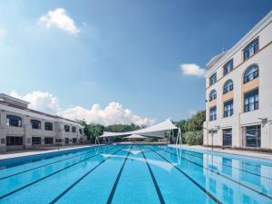 a large swimming pool between two buildings at Hilton Garden Inn Huizhou North Railway Station in Huizhou