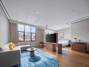 a living room with a couch and a flat screen tv at Hilton Garden Inn Huizhou North Railway Station in Huizhou