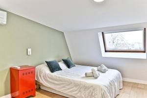 um quarto com uma cama com almofadas azuis e uma janela em Maison d'architecte à 15 min du centre de paris ! em Asnières-sur-Seine