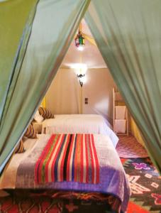 a room with two beds in a tent at Desert Camel luxury Camp in Merzouga