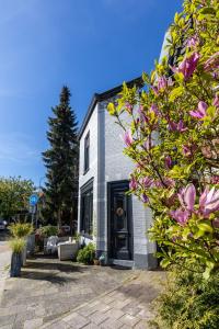 un edificio blanco con una puerta negra y algunas flores en Appartement 22 minuten van Amsterdam en Utrecht en Hilversum