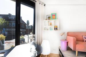 ヒルフェルスムにあるAppartement 22 minuten van Amsterdam en Utrechtのピンクのソファと窓が備わるベッドルーム1室が備わります。