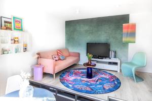 sala de estar con sofá rosa y TV en Appartement 22 minuten van Amsterdam en Utrecht en Hilversum