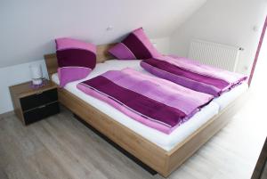 1 dormitorio con 1 cama con sábanas moradas y mesita de noche en Pension Hessenmühle, en Haundorf