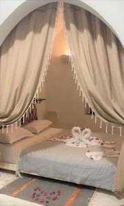 a bedroom with a bed with curtains and flowers at Hôtel Djerba Authentique - Au centre de Midoun in Midoun