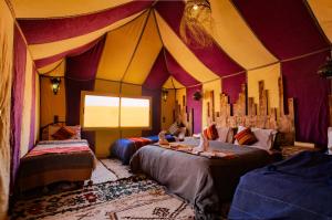 um quarto com duas camas numa tenda de circo em Sahara Dream luxury Camp em Merzouga