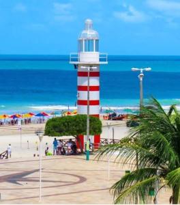 een rode en witte vuurtoren op een strand aan de oceaan bij Casa em Paracuru a 5 minutos (de carro) do centro. in Paracuru