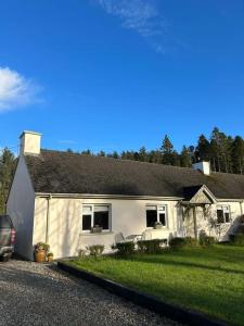 une maison blanche avec une voiture garée devant elle dans l'établissement Favour Royal Cottage - dog friendly forest escape, à Derrygorry