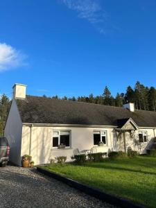 a white house with a car parked in front of it at Favour Royal Cottage - dog friendly forest escape in Derrygorry