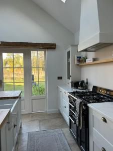 uma cozinha com armários brancos e um forno com placa de fogão em Favour Royal Cottage - dog friendly forest escape em Derrygorry