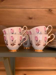 three tea cups and a tea set on a shelf at Villa Flo in Stryn