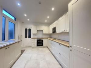 a kitchen with white cabinets and a large window at Ellergill in Keswick