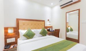 una camera con un grande letto e uno specchio di Hotel Delight a Mumbai